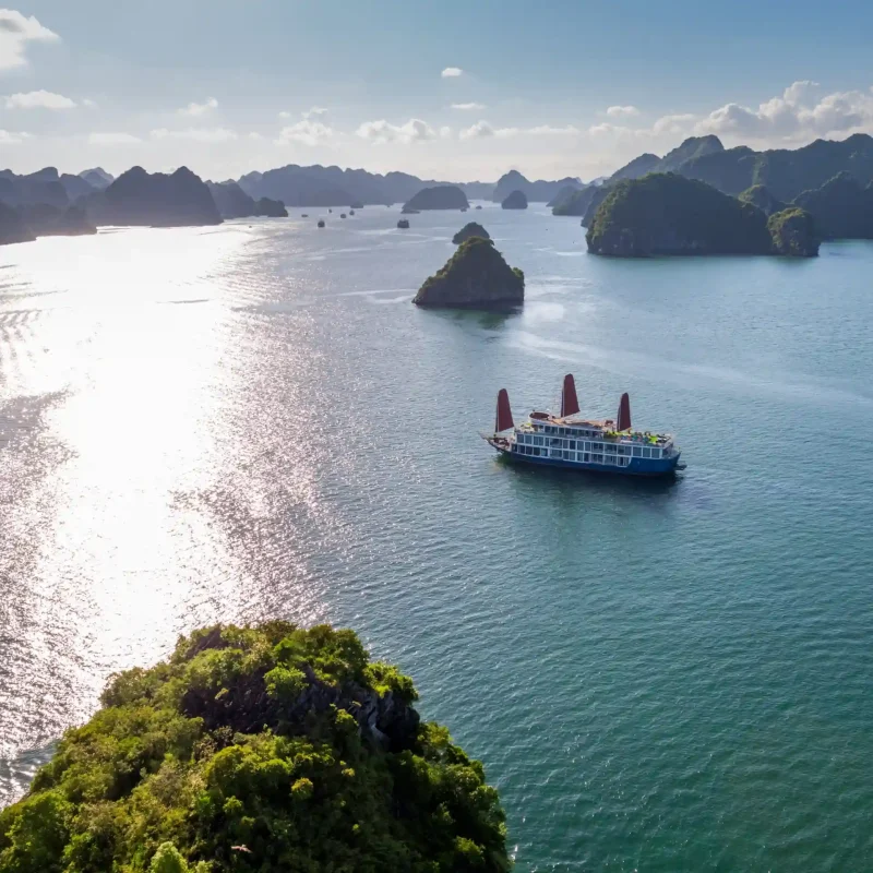 Cruise ship sailing through Lan Ha Bay at sunset